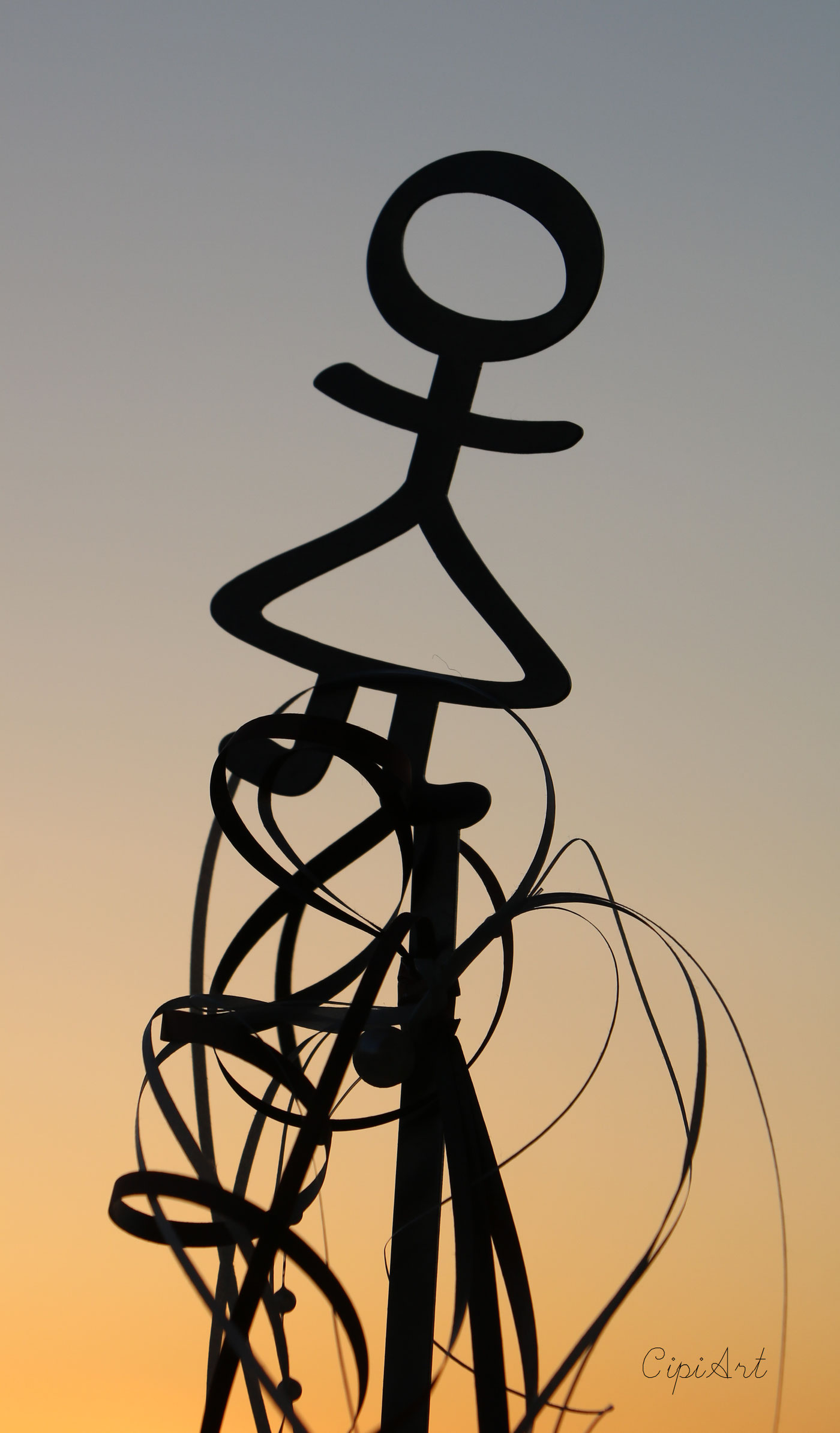 Die Frauenfigur aus dem Vereinslogo als Metallskulptur, als Silhouette vor dem Abendhimmel.